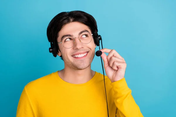 Foto di giovane bel ragazzo brunetta sguardo vuoto spazio indossare cuffie camicia gialla isolato su sfondo di colore blu — Foto Stock