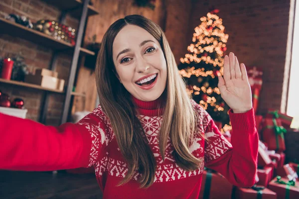 Φωτογραφία από αξιολάτρευτο γοητευτικό νεαρή γυναίκα ντυμένη κόκκινο πουλόβερ ηχογράφηση το νέο έτος βίντεο κουνώντας το χέρι χαμογελώντας εσωτερικό δωμάτιο σπίτι — Φωτογραφία Αρχείου