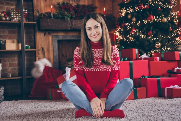 Foto van schattige zoete volwassen dame dragen rode trui glimlachende zittende benen gekruist genieten van kerst binnen huis kamer — Stockfoto