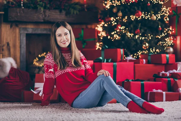 Foto de bela encantadora jovem mulher vestida camisola vermelha sentado chão celebrando o ano novo sorrindo dentro de casa quarto casa — Fotografia de Stock