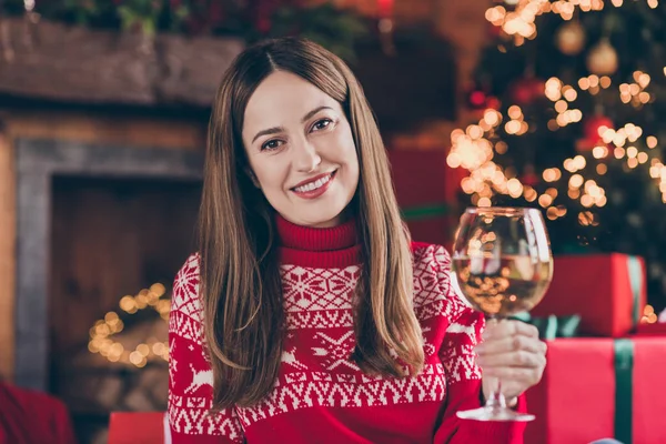 Foto de encantadora jovem mulher vestida camisola vermelha bebendo vinho branco celebrando o ano novo sorrindo dentro de casa quarto casa — Fotografia de Stock