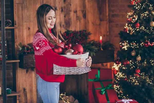 Φωτογραφία από ονειρικό γοητευτικό ώριμη κυρία φορούν κόκκινο πουλόβερ χαμογελώντας διακόσμηση χριστουγεννιάτικο δέντρο σε εσωτερικούς χώρους σπίτι δωμάτιο — Φωτογραφία Αρχείου