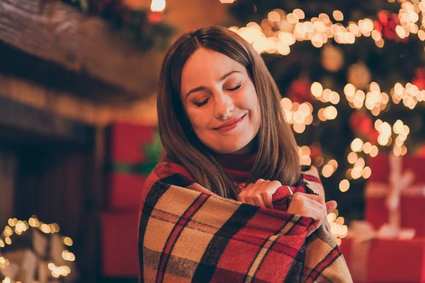 Φωτογραφία από αξιολάτρευτο ονειρική νεαρή γυναίκα ντυμένη κόκκινο πουλόβερ γιορτάζει το νέο έτος τροχαίο ζεστή κουβέρτα χαμογελώντας σε εσωτερικούς χώρους σπίτι δωμάτιο — Φωτογραφία Αρχείου
