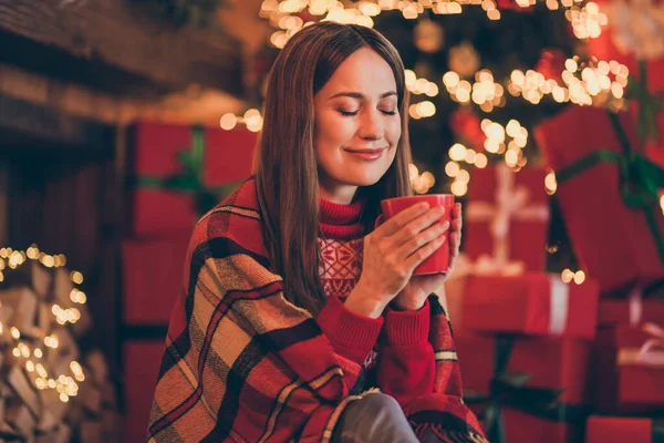 Φωτογραφία από ονειρεμένη χαρούμενη νεαρή γυναίκα ντυμένη κόκκινο πουλόβερ πίνοντας το νέο έτος ζεστό eggnog χαμογελώντας σε εσωτερικούς χώρους σπίτι δωμάτιο — Φωτογραφία Αρχείου