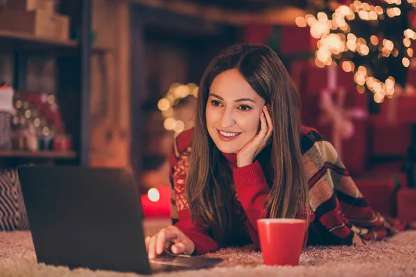 Foto av söt charmig mogen dam bära röd pullover leende skriva modern enhet jul grattis inomhus hus hem rum — Stockfoto