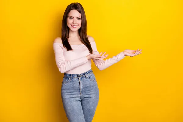 Foto der optimistischen brünetten Dame Standpunkt leeren Raum tragen rosa Hemd Jeans isoliert auf gelbem Hintergrund — Stockfoto