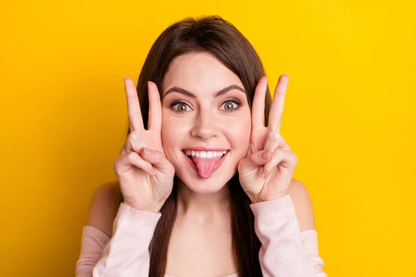 Zdjęcie młodego funky śmieszne śmieszne uśmiech wesoły dziewczyna stick-out język pokazując v-znak izolowane na żółtym tle kolor — Zdjęcie stockowe