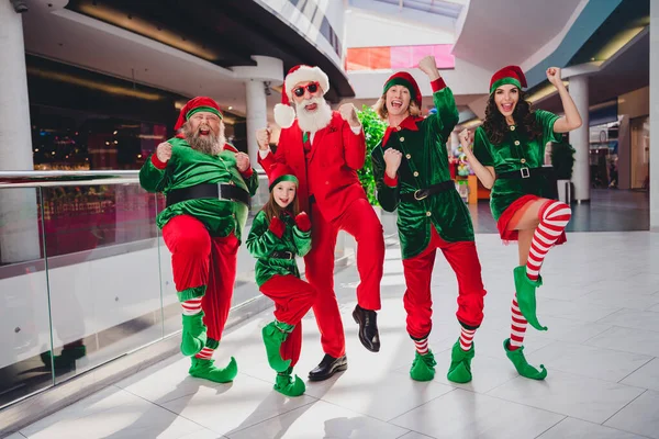 在超级市场购物中心，五位冠军风趣朋友穿着圣诞小精灵服装欣赏圣诞表演的照片 — 图库照片