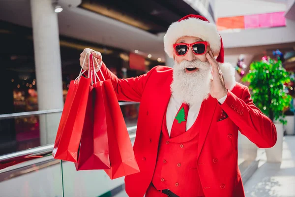 Zdjęcie zszokowany Mikołaj kupić specjalną ofertę okazje otrzymać cashback nosić okulary przeciwsłoneczne kapelusz czerwony smoking w centrum supermarketu — Zdjęcie stockowe