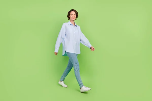 Full kropp profil sida foto av ung kvinna glad positiv leende gå promenad möte isolerad över grön färg bakgrund — Stockfoto