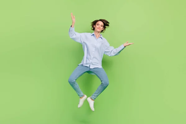 Pleine longueur photo de joyeuse jeune femme sauter lever les mains sourire cool isolé sur fond de couleur verte — Photo