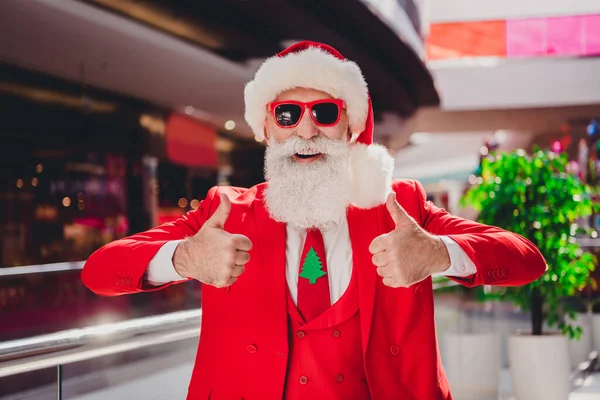 Retrato de Santa alegre atraente mostrando anúncio duplo thumbup anúncio barganha festal no shopping center dentro de casa — Fotografia de Stock