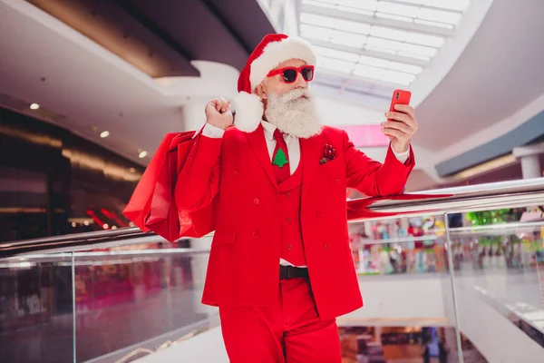 魅力的な髭を生やした高齢者の肖像サンタは屋内ショッピングモールでデバイスを使用してウェブ上の贈り物を注文する商品を購入する — ストック写真