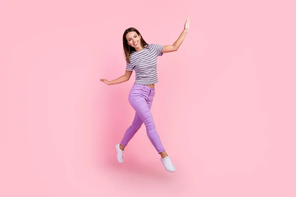 Foto de bastante adorable joven dama usar traje a rayas sonriendo saltando alto caminando aislado color rosa fondo — Foto de Stock