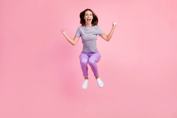 Foto van grappige gelukkige jonge vrouw gekleed gestreepte kleding springen hoog rijzende vuisten glimlachen geïsoleerde roze kleur achtergrond — Stockfoto