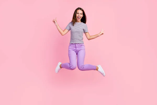 Fénykép aranyos vicces fiatal nő öltözött csíkos ruhák ugrás magas mutatja két v-jelek mosolygó elszigetelt rózsaszín háttér — Stock Fotó