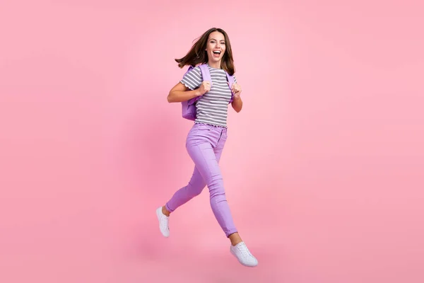 Foto de funky encantadora joven dama usar a rayas traje mochila sonriente saltando alto caminando aislado color rosa fondo —  Fotos de Stock