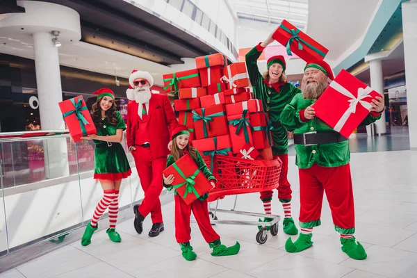 Ritratto di attraenti amici funky allegri persone che tengono scatole regalo divertirsi tempo vigilia di festa al centro commerciale al chiuso — Foto Stock