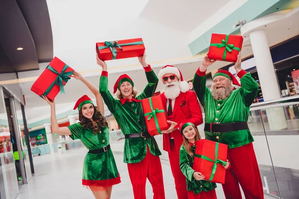 Portrait d'attrayant gai elfes de groupe branchés tenant des boîtes-cadeaux acheter avoir du plaisir se réjouissant repos veille festal temps au magasin à l'intérieur — Photo