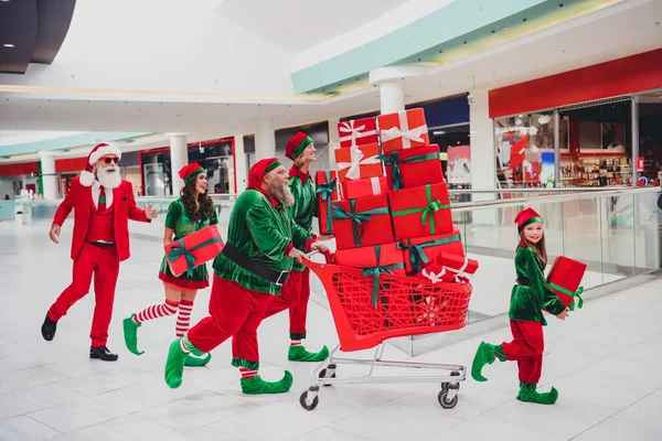 Lunghezza intera dimensione del corpo vista di attraente allegro gruppo funky elfi in esecuzione l'acquisto portando regali di Natale vigilia tradizione al negozio al chiuso — Foto Stock