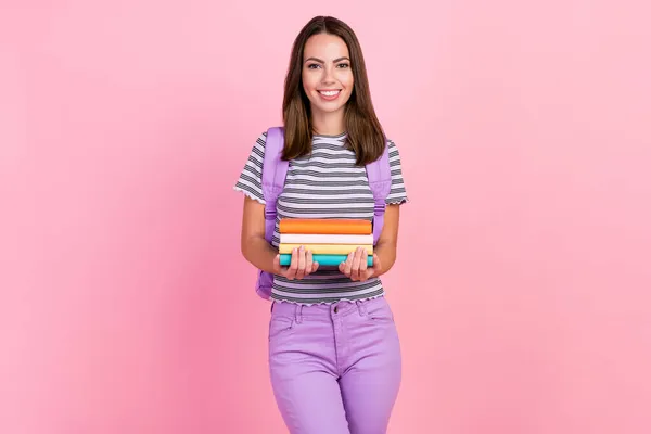 Foto de divertida dulce mujer joven vestida a rayas ropa mochila celebración diarios sonriendo aislado color rosa fondo — Foto de Stock