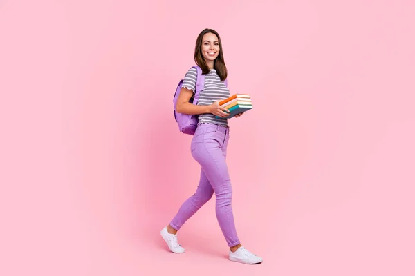 Foto de linda adorable joven dama usar traje a rayas mochila sonriente caminar celebración copybooks aislado color rosa fondo — Foto de Stock