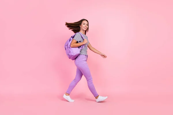 Bild av charmig rolig ung kvinna klädd randiga kläder ryggsäck promenader vind blåser leende isolerad rosa färg bakgrund — Stockfoto