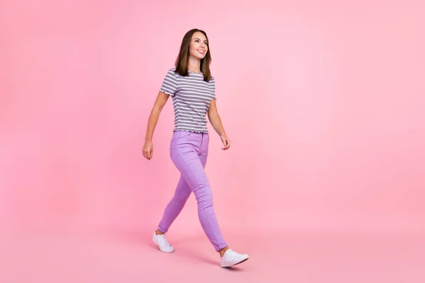 魅力的なかなり若い女性の服を着て縞模様の服を歩いて空のスペース笑顔孤立ピンク色の背景 — ストック写真
