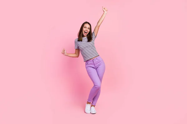 Foto de dulce afortunada joven dama usar traje a rayas sonriente baile levantamiento puño aislado color rosa fondo — Foto de Stock