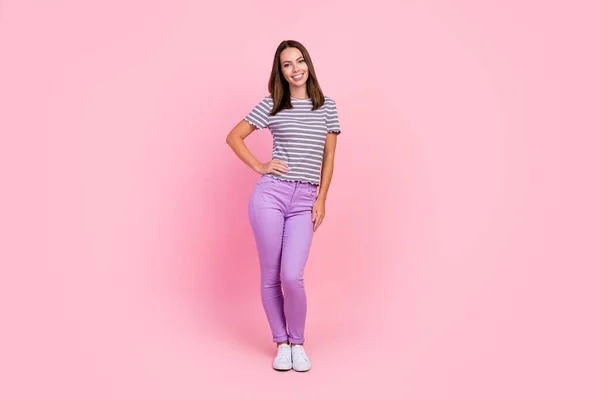 Foto de encantadora dulce joven dama usar traje a rayas sonriente brazo de pie cintura aislado color rosa fondo — Foto de Stock