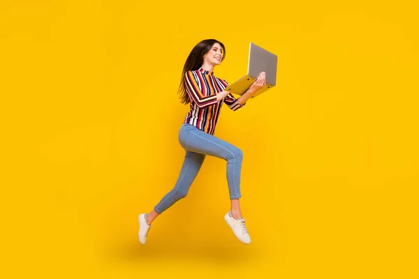 Tamanho total do corpo foto menina em roupas casuais saltando trabalhando no computador isolado cor amarela brilhante fundo — Fotografia de Stock