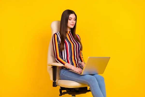 Foto samping profil wanita muda tersenyum positif duduk sambil mengetik laptop email yang terisolasi dengan latar belakang warna kuning — Stok Foto
