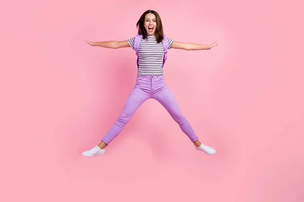 흥분 한 젊은 숙녀가 줄 무늬 배낭을 메고 별처럼 높이 뛰어 오르는 핑크 색 배경 사진 — 스톡 사진