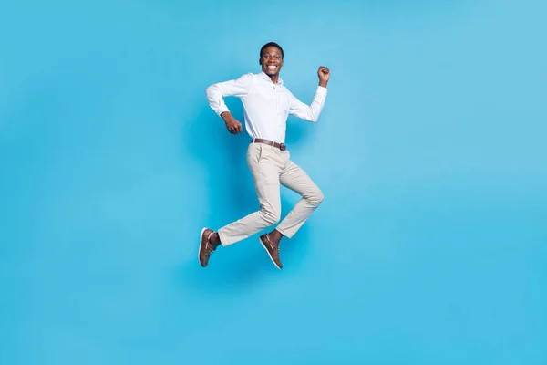 Foto van geluk mooie donkere huid guy gekleed formele shirt neuken hoog rijzende vuist glimlachen geïsoleerde blauwe kleur achtergrond — Stockfoto