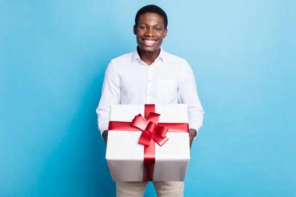 Fotografie roztomilé tmavé kůže chlap oblečený formální košile vám dárek box s úsměvem izolované modré barvy pozadí — Stock fotografie