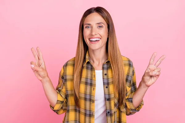 Foto av glada positiva unga kvinna gör fingrar cool v-tecken njuta isolerad på rosa färg bakgrund — Stockfoto