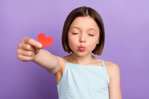 Foto de lindo penteado marrom menina pequena beijo golpe dar coração desgaste azul top isolado no fundo cor violeta — Fotografia de Stock