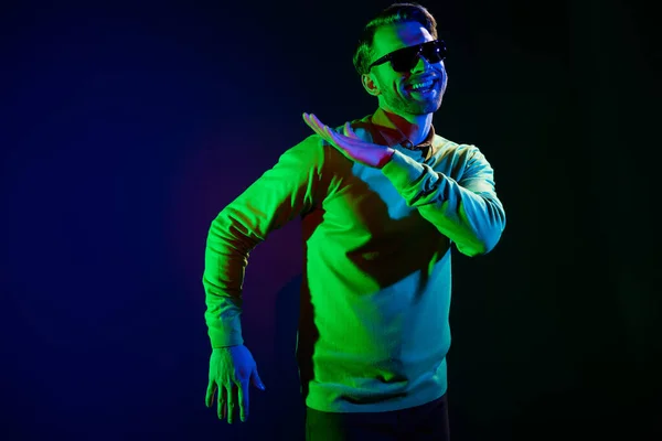 Foto de jovem funky cara dança desgaste óculos suéter isolado no fundo de cor azul escuro — Fotografia de Stock