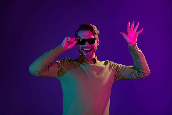 Φωτογραφία πορτρέτο του χαμογελαστού άνδρα φορώντας γυαλιά ηλίου κουνώντας τα χέρια απομονώνονται σε βιολετί φόντο χρώμα — Φωτογραφία Αρχείου