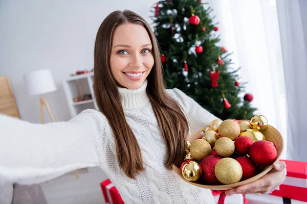 魅力的な幸せな若い女性の写真家のフラット内部クリスマスの手のボールの装飾の装飾を保持します。 — ストック写真