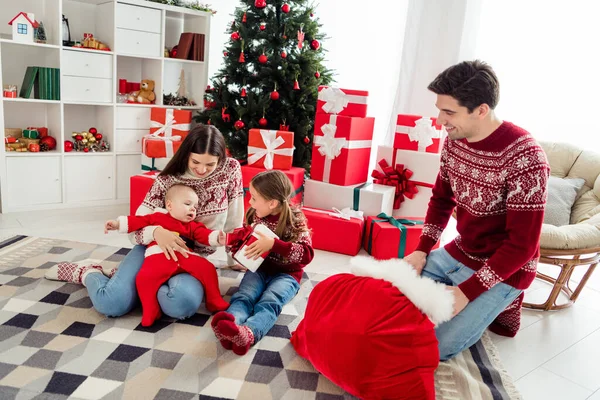 Full lenght photo of young cheerful family happy positive smile santa claus bag present box new year winter indoors — Stock Photo, Image