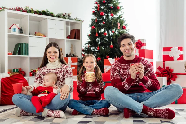 Фотография в полный рост молодой веселой семьи, счастливой позитивной улыбкой, чаепитие горячим кофе и атмосфера в помещении — стоковое фото