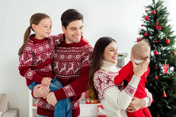 Foto de alegre família positiva abraçar criança desfrutar de decoração noel usar camisola em casa decorada x-mas em casa dentro de casa — Fotografia de Stock