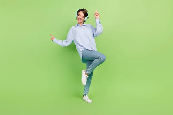 Pleine longueur photo de jeune femme heureux sourire positif danse écouter musique écouteurs isolés sur fond de couleur verte — Photo