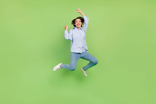 全长照片中快乐而积极的年轻女子跳起来，手指空空如也，被绿色的背景隔开 — 图库照片