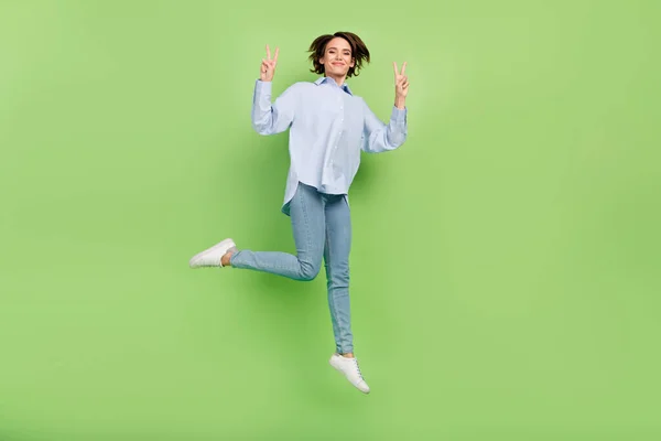 Full body photo of cheerful young positive happy woman jump up make v-sign isolated on green color background — Stock Photo, Image