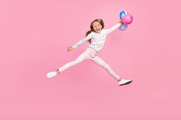 Fotografie legrační a-student žák malá dáma skok držet balónky nosit tečkované pyžama izolované růžové barvy pozadí — Stock fotografie