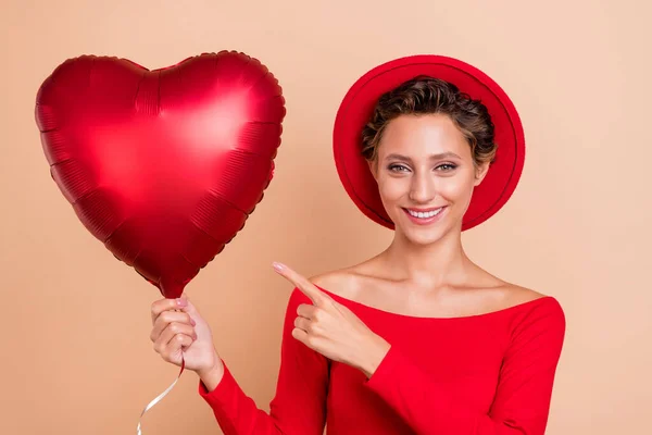 Photo de joyeux charmant jeune belle femme pointe du doigt coeur ballon sourire isolé sur fond de couleur beige — Photo