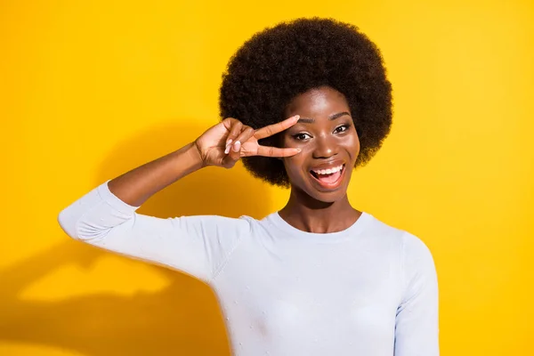 Портрет оптимистичной брюнетки короткие волосы леди показать V-знак носить белый пуловер изолированы на ярком желтом фоне цвета — стоковое фото