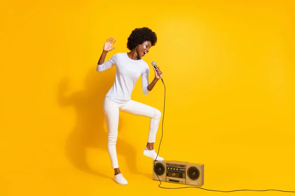 Teljes méretű profil fotó optimista rövid haj hölgy énekel mikrofon kopás fehér pulóver nadrág cipő elszigetelt sárga háttér — Stock Fotó